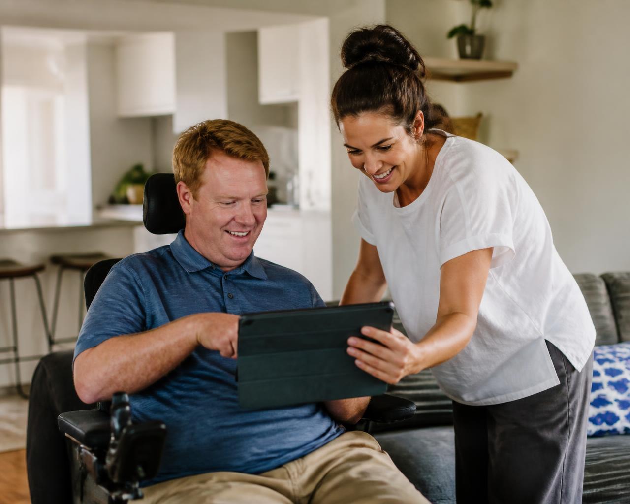 A support worker and participant laughing together at home